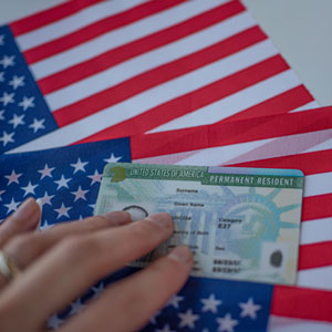 Woman touching a U.S. permanent residency card on top of two U.S. flags - Robinett Law PLLC