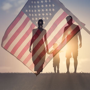 Couple with one child walking together in front of a U.S. flag - Robinett Law PLLC